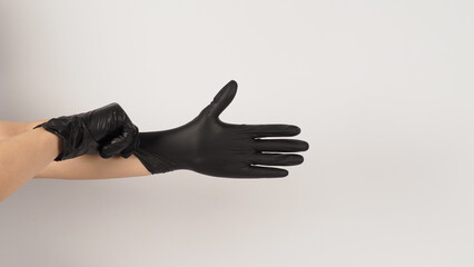 The hand is pulling black latex gloves  on white background.