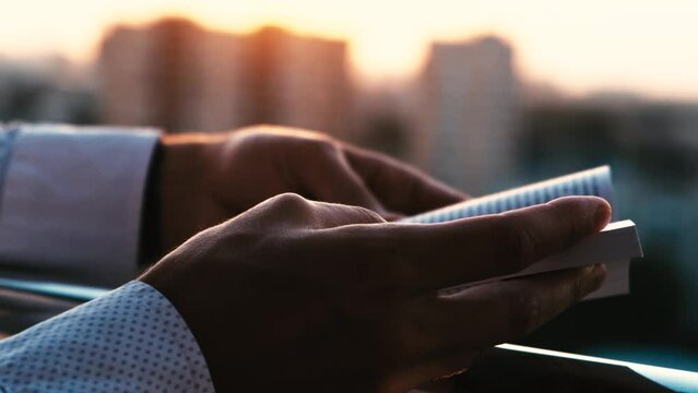 Man reading a book or bible while turning pages at sunset