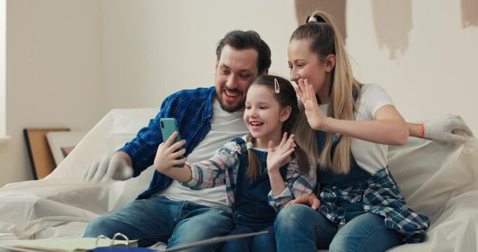 Happy family talking with friends on online conference. The girl tells about the fact that she wants to have green walls in her children's room. Parents share their experience in home renovation.