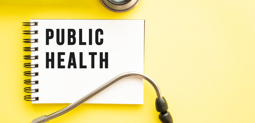 Text PUBLIC HEALTH on notebook with stethoscope on yellow background.