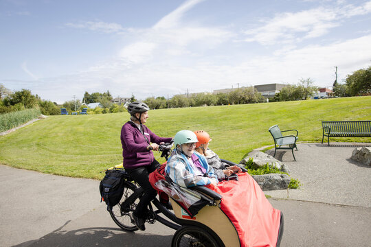 Senior woman bicycling elderly friends in rickshaw in sunny park