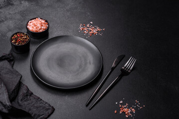 Empty black plate over dark stone background with free space. Top view