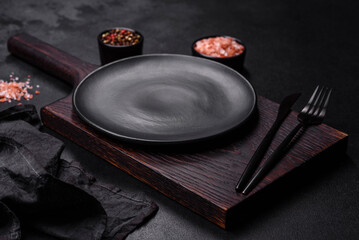 Empty black plate over dark stone background with free space. Top view - Powered by Adobe