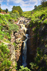 Fototapeta na wymiar long waterfall with green vegetation and cloud sky in the mogote, el oro mexico state