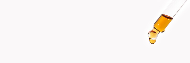 Pipette with drop of serum or cosmetic liquid close-up on white background. The appearance of the texture of the gel. Transparent laboratory glassware. Medicine and beauty concept.