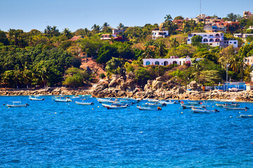 boats on the coast with mountain in the background and houses, in puerto escondido oaxaca 