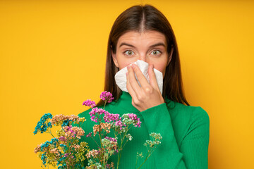 Portrait of woman blowing nose in handkerchief shocked with allergic reaction to flowers blooming