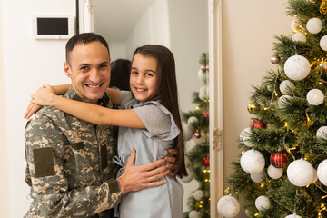 Armed Forces Soldier Hugging his daughter In Front Christmas Tree.