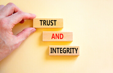 Trust and integrity symbol. Concept words Trust and integrity on wooden blocks. Businessman hand....