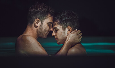 Gay couple relaxing in swimming pool. LGBT. Two young men kissing and hugging. Young men romantic family in love. Happiness concept - 534585544
