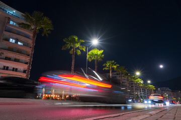 Long exposure with vehicle light streaks at night on the harbor by the sea in Vloe, Albania