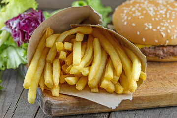 Close-up view of french fries in a paper with hamburger and green salad