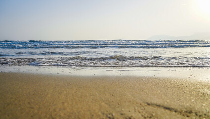 foamy bubble waves crashing gently from the sea to the beach at sunset, selective focus to wave, sea and sand are blurred