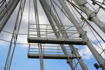 Fototapeta na wymiar Zwei übereinanderstehende graue Sprungbretter aus Stahl an weißen Karussellpfeilern vor blau-weißem Himmel 