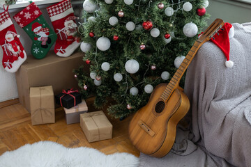 Gifts and presents under the xmas tree. Christmas tree with christmas decorations and christmas lights and acoustic guitar on background.