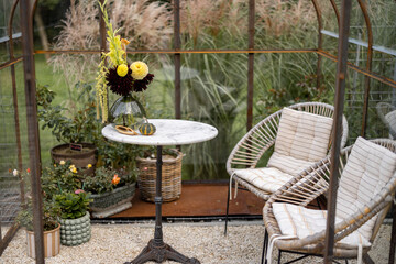 Beautiful bouquet of flowers in vase on the table in greenhouse with fogged up glass. Cozy place, floral concept