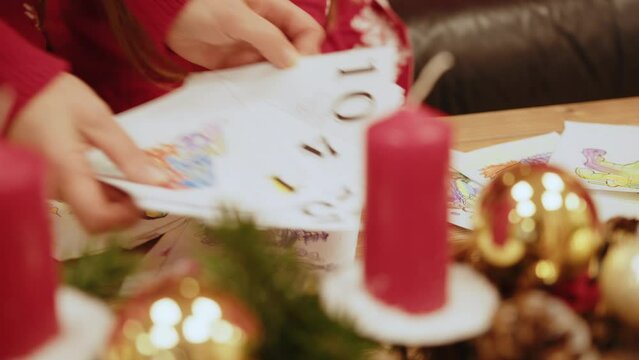 Little girl draw at the table near the fireplace and the Christmas tree. Child with a letter for santa. Happy little girl draw a picture for santa by the New Year tree in the room