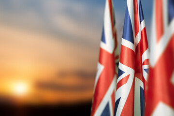 National flags of United Kingdom on a flagpole on sunset sky background. Lowered UK flags. Background with place for your text.