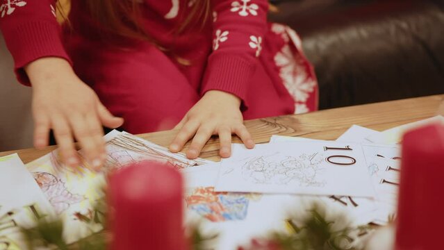 Little girl drawing toy, sitting on sofa in decorated living room. Small child painting deer, using colorful pencils. Hobby and leisure during christmas holidays. New year atmosphere, happy childhood