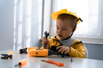 Obraz na płótnie Canvas Child play with work tools at home, dreams to be an engineer. Little boy builder. Education, and imagination, purposefulness concept. Kid and wrench.