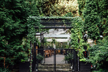 Biophilic Design, biophilia in city street, connecting people and nature. Biophilic Design Restaurant with Green plants and trees. Street Cafe botanical garden outdoor.