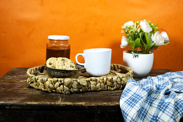 cup coffee with homemade chocolate chip cookies with honey jar and roses flowers on wood table