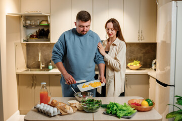 Lovely family couple preparing vegetable vegan salad together in kitchen. Healthy food and diet concept lifestyle. Cook at home