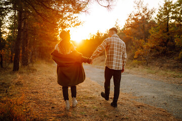 Happy couple in love newlyweds in casual clothes travel together, hike and walk in the autumn forest in nature.