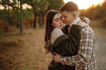Happy couple in love newlyweds in casual clothes travel together, hike and walk in the autumn forest in nature.