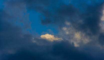 Naklejka na ściany i meble White cumulus cloud among dark rain clouds.