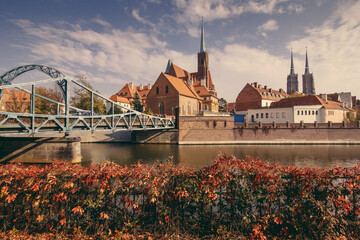 View  of medieval town: Tumski Bridge between the islands of Wyspa Piasek and Ostrow Tumski and Roman Catholic Church of St. NMP in autumn. Poland, Wroclaw.