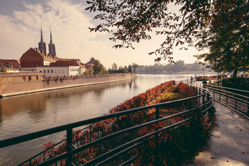 View  of medieval town: Tumski Bridge between the islands of Wyspa Piasek and Ostrow Tumski and Roman Catholic Church of St. NMP in autumn. Poland, Wroclaw.