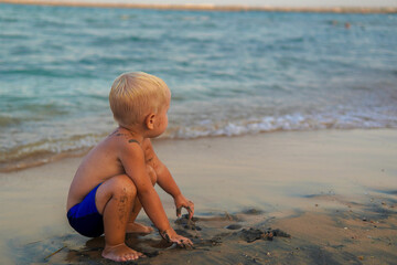 little boy with blonde hair having fun on the beach