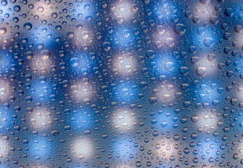 Naklejka na ściany i meble Macro of grid of illuminated blue and yellow lights in an LED panel, seen through wet pane of glass, nobody