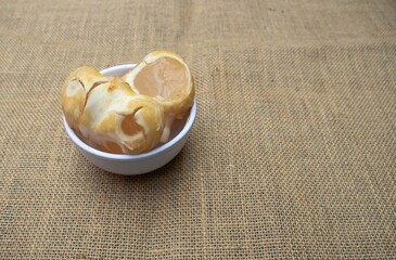 Ice Apple or Palmyra Palm Fruit in White Bowl Isolated on Burlap Fabric with Copy Space, Also Known...