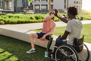 Multiracial people with physical disabilities greeting each other outdoor - Focus on right man...
