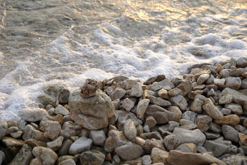 Fototapeta na wymiar Pebble beach with big pebbles near the bubbling sea water