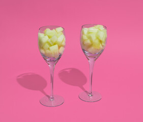 Luxury glasess filled with Honeydew melon cubes on a pink background