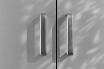 A pair of simple cabinet handles are grey and shade on a light background. Black and white