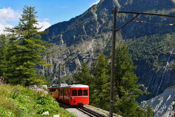A red tourist train on the rack railway towards the station of Montenvers at the Mer de Glace in...