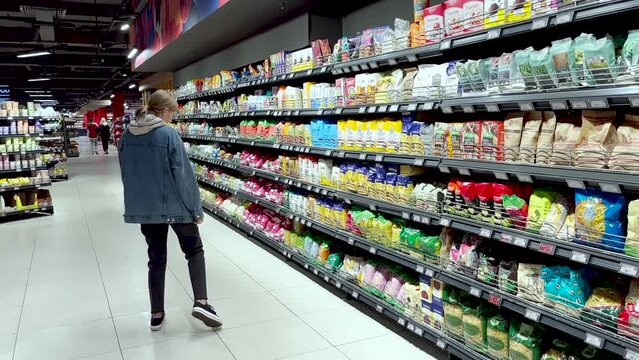 a woman chooses a product on the shelves of a supermarket