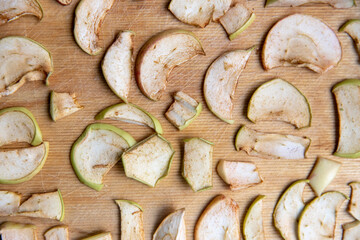 Sliced apple slices are laid out on a cutting board and dried in the kitchen. Dried apples