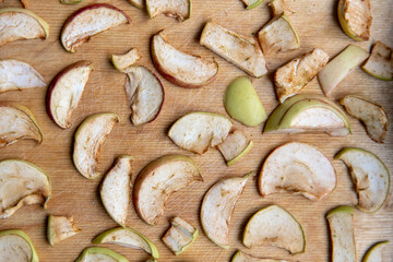 Sliced apple slices are laid out on a cutting board and dried in the kitchen. Dried apples