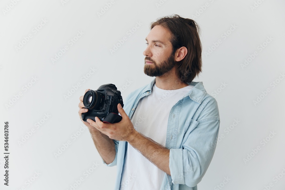 Wall mural a male hipster photographer in a studio against a white background looks through the camera viewfind