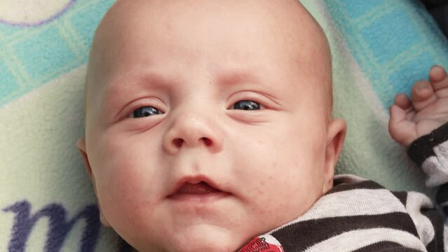 4k footage video. Close up newborn baby sneezing child lying in baby carriage stroller buggy having fun playing, looking at her mother, smiling infant. Outside walking in pushchair, fresh air

