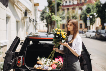 Florist placing flowers in car. Flower delivery concept.