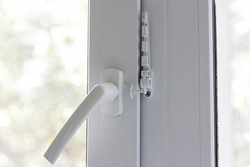 Close-up of a balcony door handle, double-glazed window fixing with a latch and a comb, a door frame. The concept of repairing doors and windows of a house