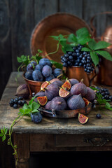 Figs, grapes and plums on an old wooden table. Still life in rustic retro style