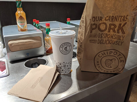 California - October 15, 2019: Chipotle Mexican Grill food bag and drink on condiment counter. With more than 1600 locations.
