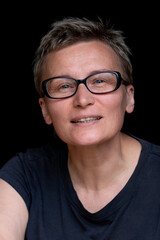 Fototapeta premium Portrait of caucasian woman with short haircut and black-rimmed glasses on black background, close-up. Emotions on face. High quality photo